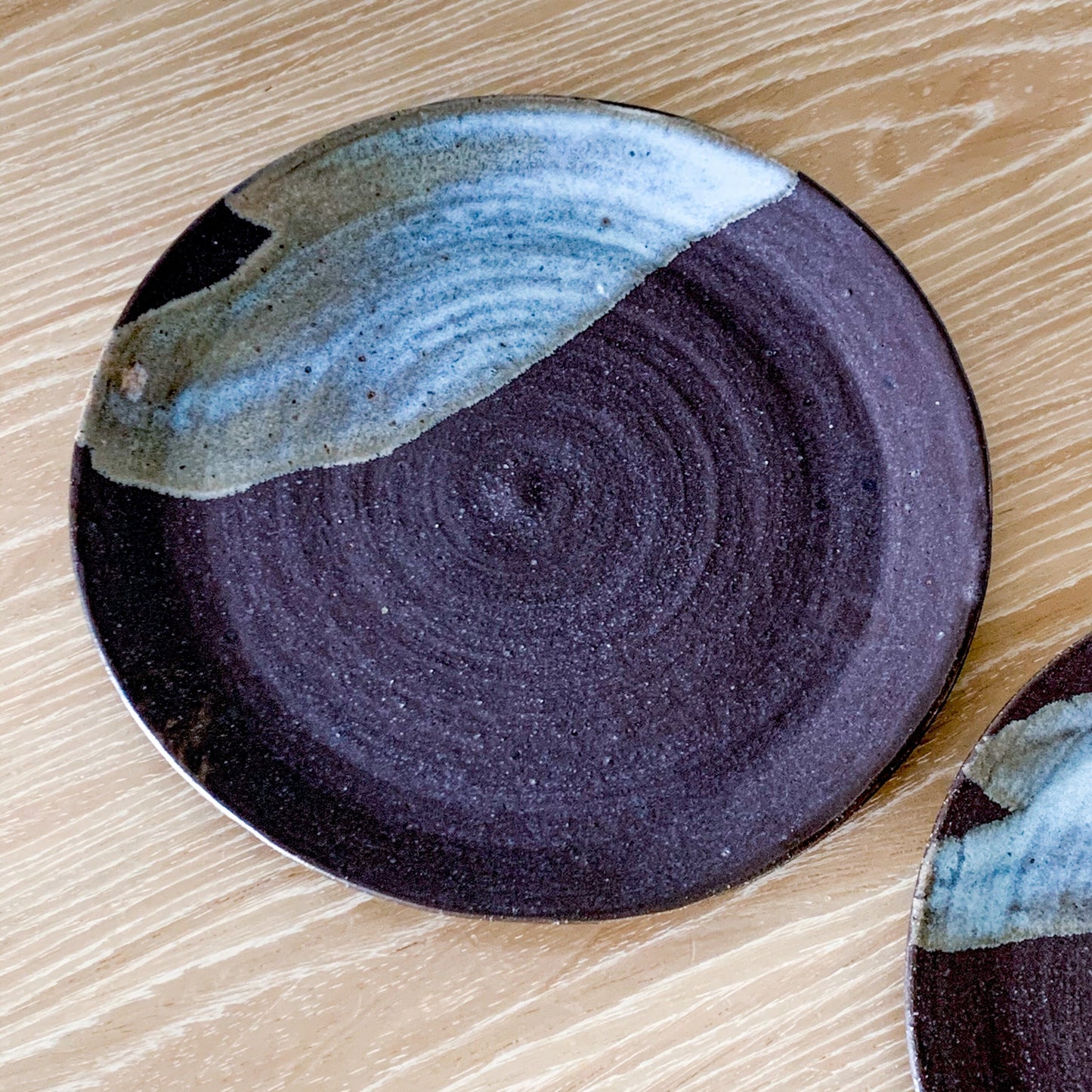 Pottery plate in matt brown color with shiny blue splash