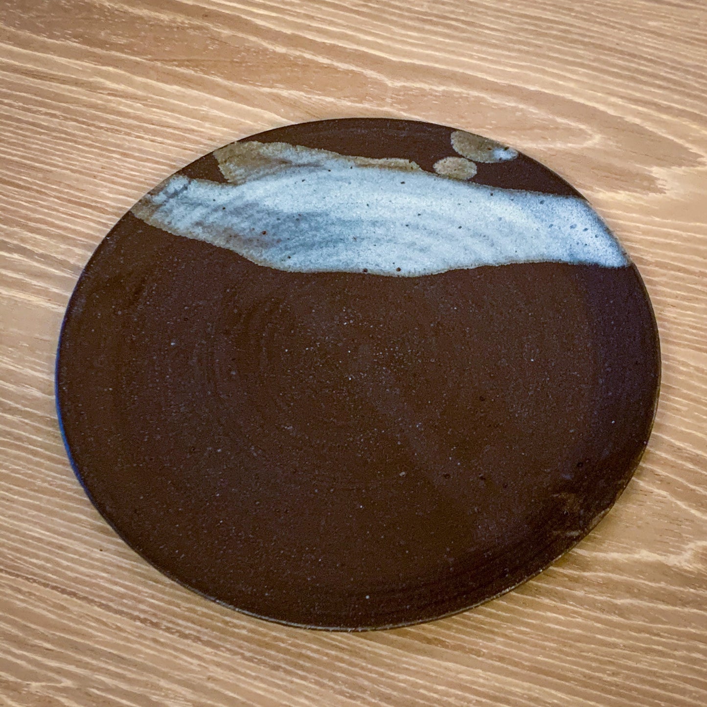 Pottery plate in matt brown color with shiny blue splash